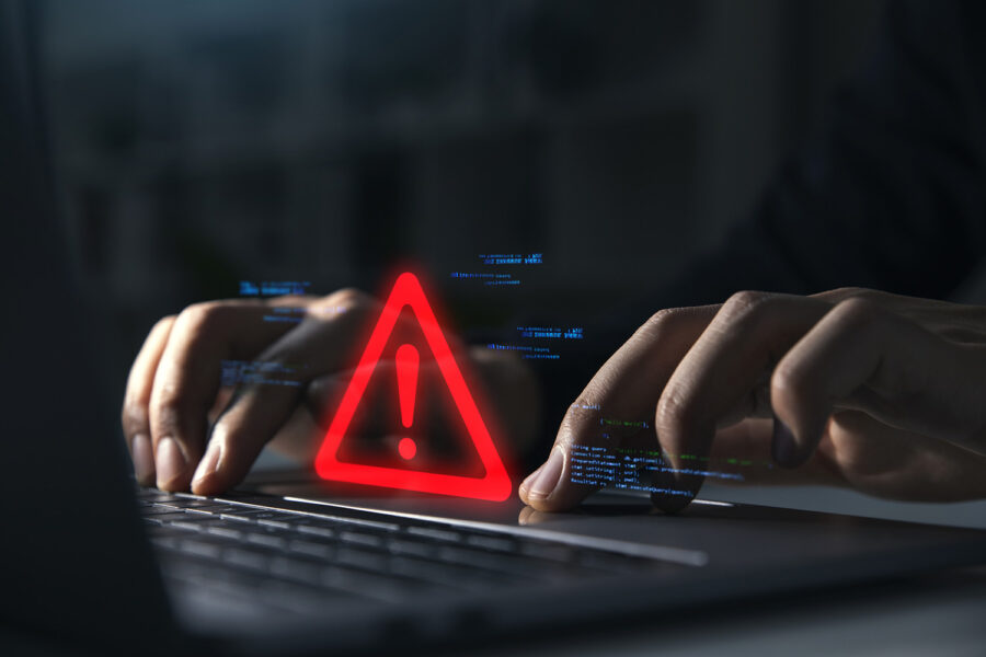 Hand of businessman using laptop with caution warning sign